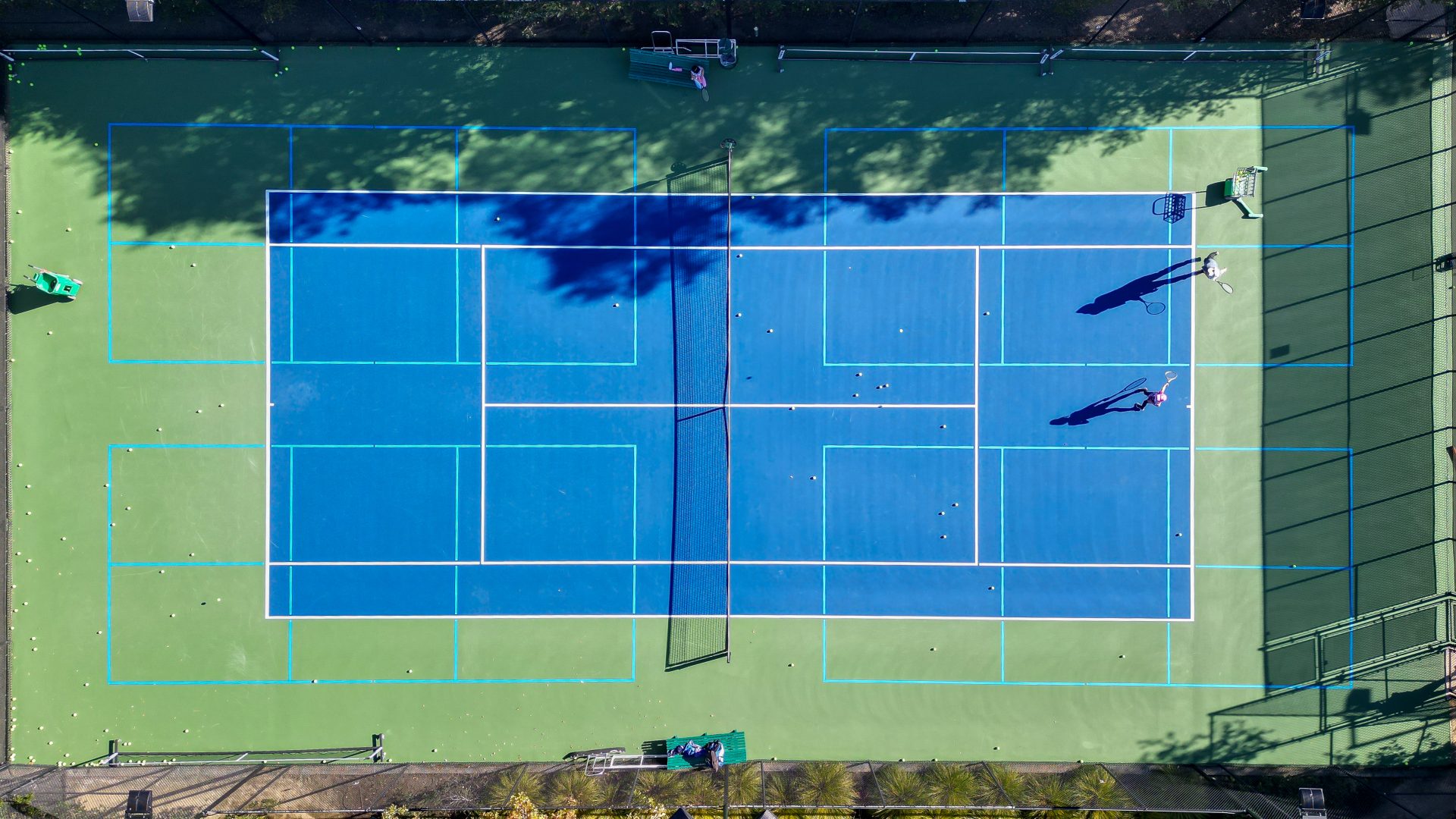 Aerial view of a tennis court at Foothills Tennis & Swimming Club in Palo Alto. The courts have been resurfaced using Plexipave acrylic resurfacer in dark blue and medium green with four sets of light blue blended pickleball lines painted on.
