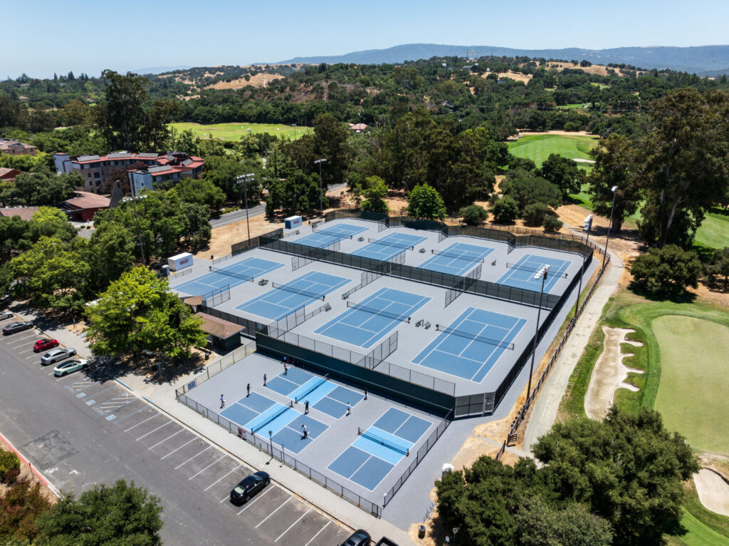 Aerial view of 3 pickleball courts and 8 tennis courts at Stanford University, West Campus. All courts were reconstructed using the slipsheet method and surfaced with Har-tru Proflex acrylic coating in Champion Blue, Dark Grey and Light Blue